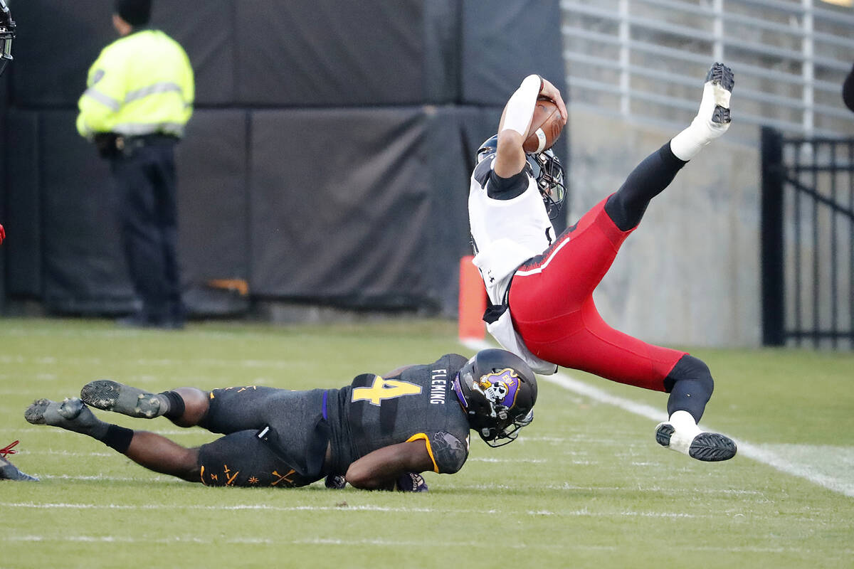 East Carolina's Malik Fleming (4) takes down Cincinnati quarterback Desmond Ridder (9) during t ...