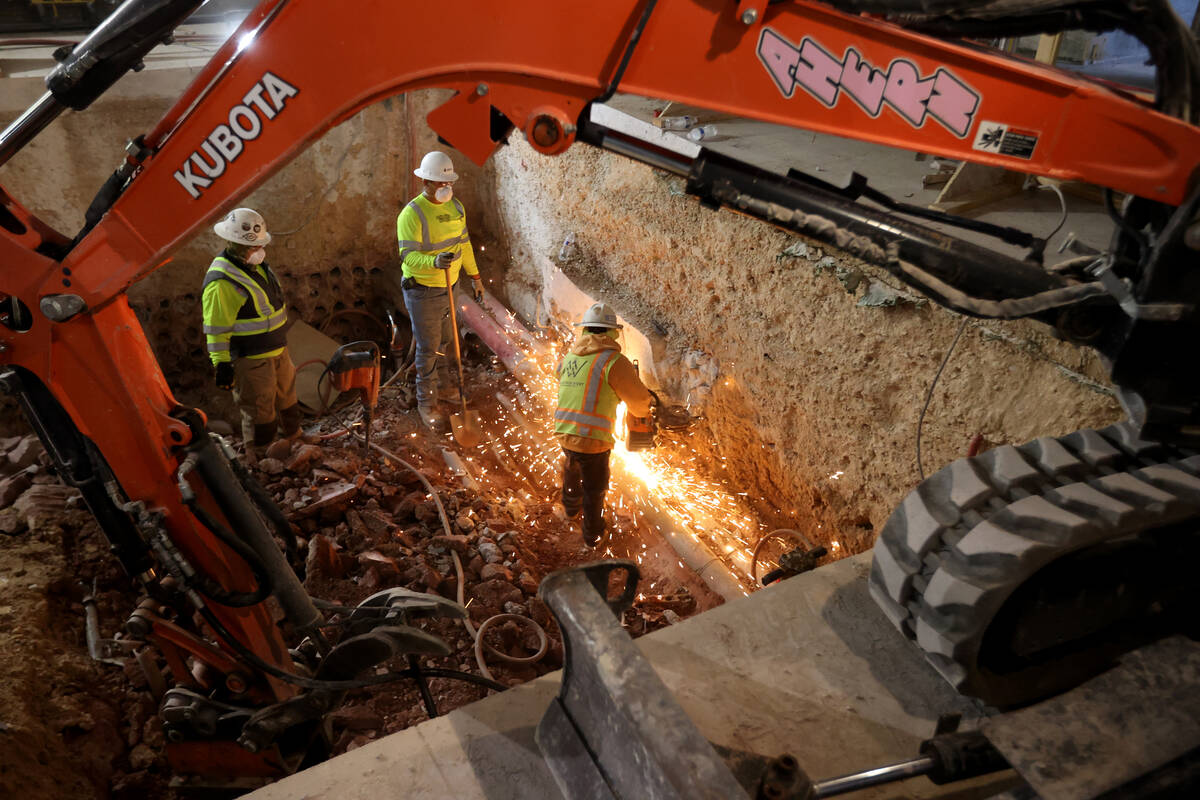 Workers remove old electrical conduit in preparation for new electrical as construction continu ...