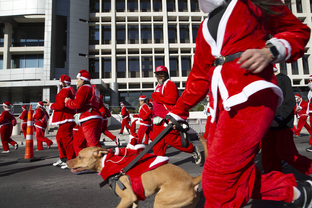 Runners and their pets make way down Las Vegas Boulevard during The Las Vegas Great Santa Run o ...