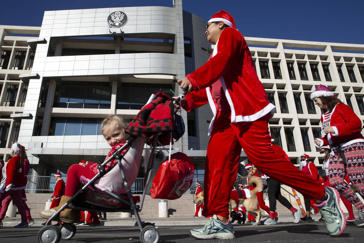 Runners and their pets make way down Las Vegas Boulevard during The Las Vegas Great Santa Run o ...