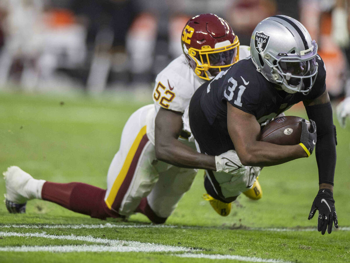 Raiders running back Peyton Barber (31) leaps forward past Washington Football Team middle line ...