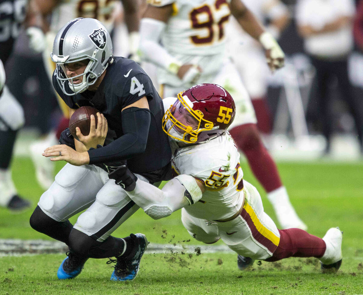 Raiders quarterback Derek Carr (4) is brought down by Washington Football Team outside lineback ...