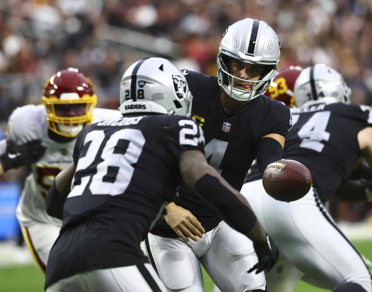 Raiders quarterback Derek Carr (4) hands off the ball to running back Josh Jacobs (28) during t ...