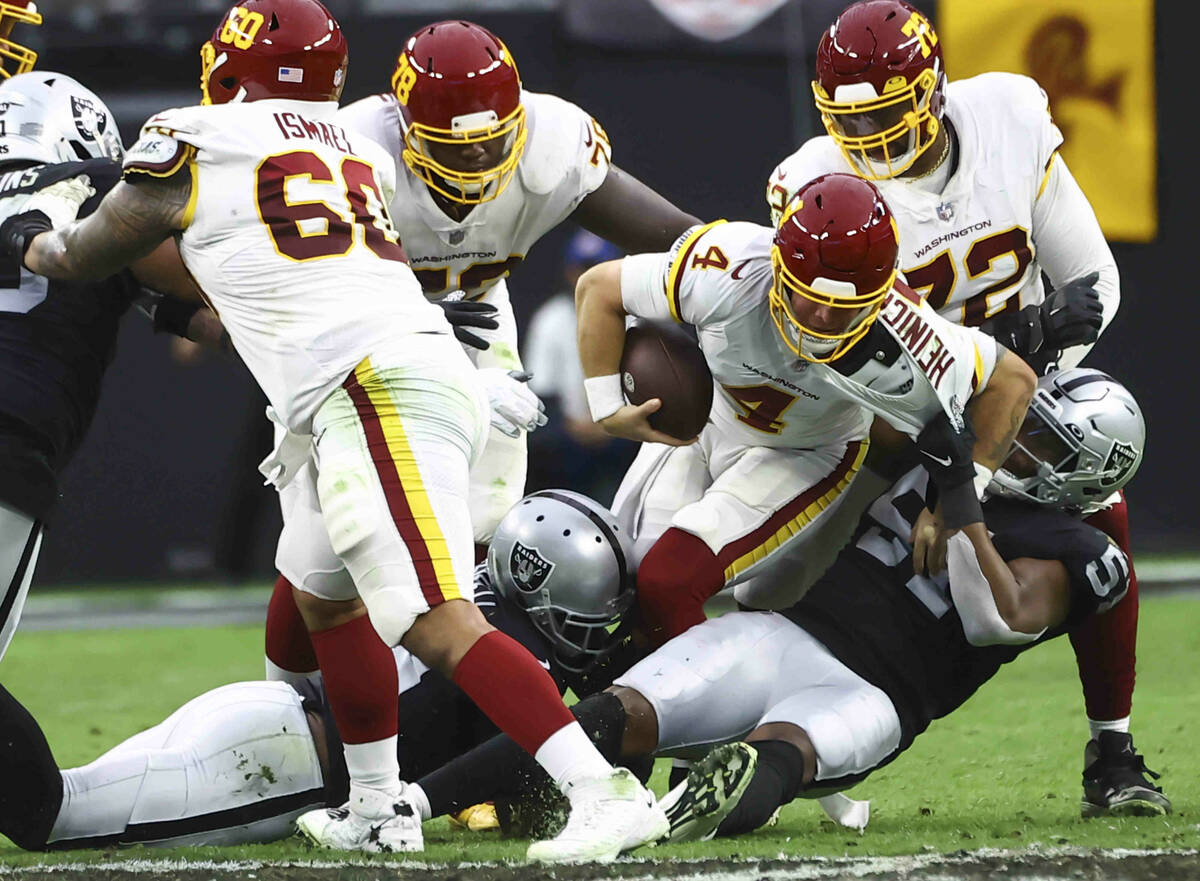 Washington Football Team quarterback Taylor Heinicke (4) gets sacked by Raiders defensive end M ...