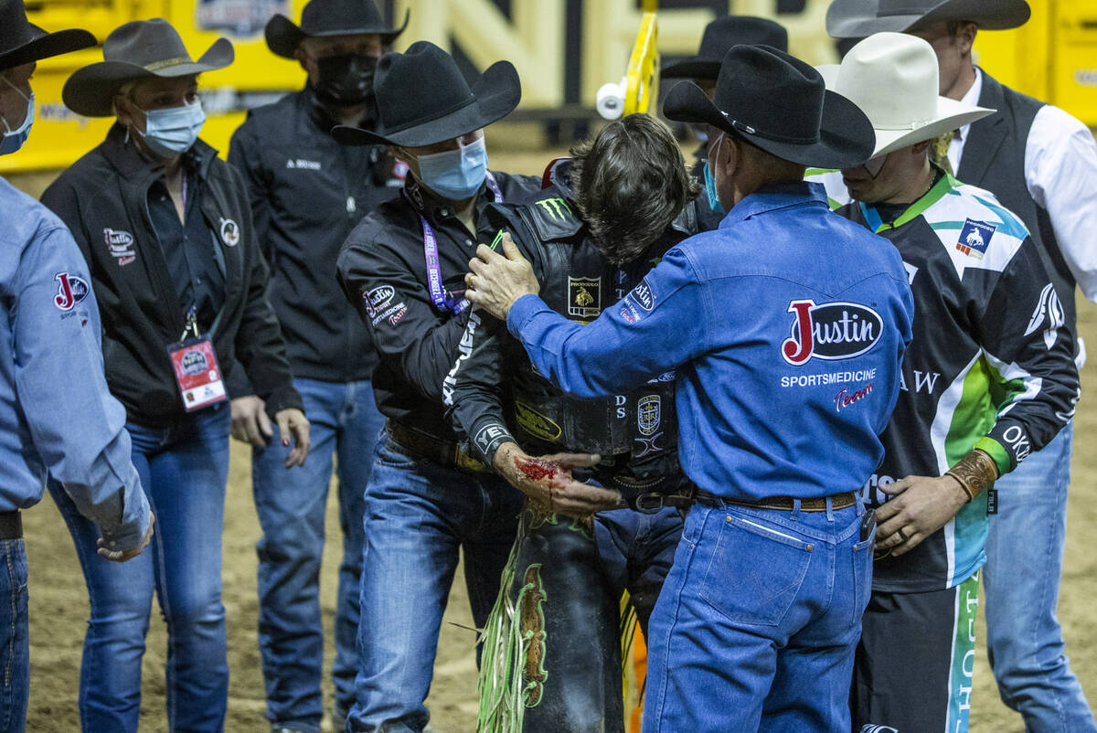 J.B. Mauney of Cotulla, TX., is assisted from the arena after injured riding Johnny Thunder in ...