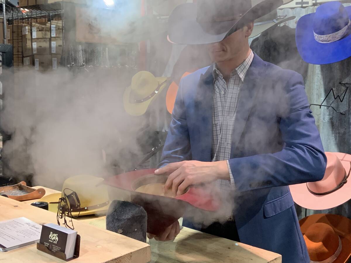 A hatmaker plies his trade, reshaping a young girl's cowboy hat at a booth inside The Cowboy Ch ...