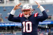 New England Patriots quarterback Mac Jones yells as he runs down the sidelines prior to an NFL ...