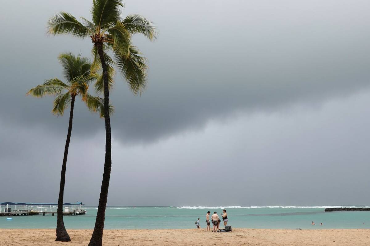 With storm clouds in the background, beachgoers are seen on Waikiki Beach, Monday, Dec. 6, 2021 ...