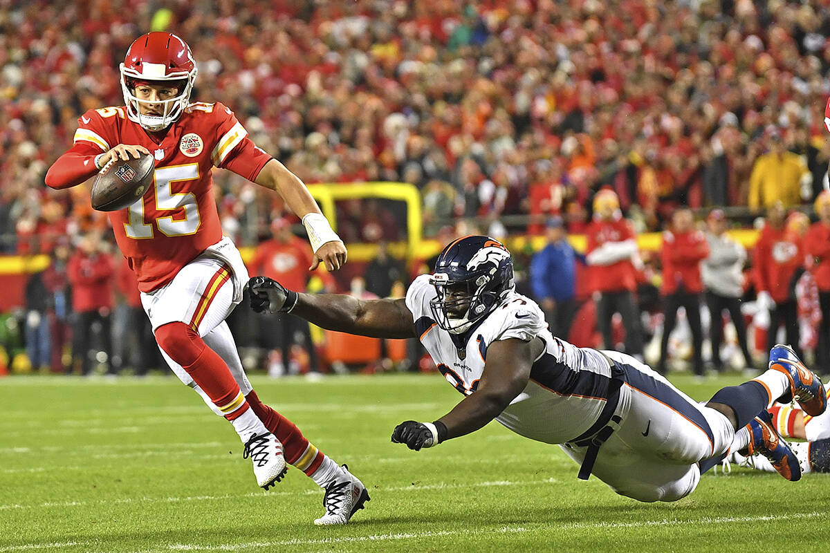Kansas City Chiefs quarterback Patrick Mahomes (15) scrambles away from Denver Broncos defensiv ...