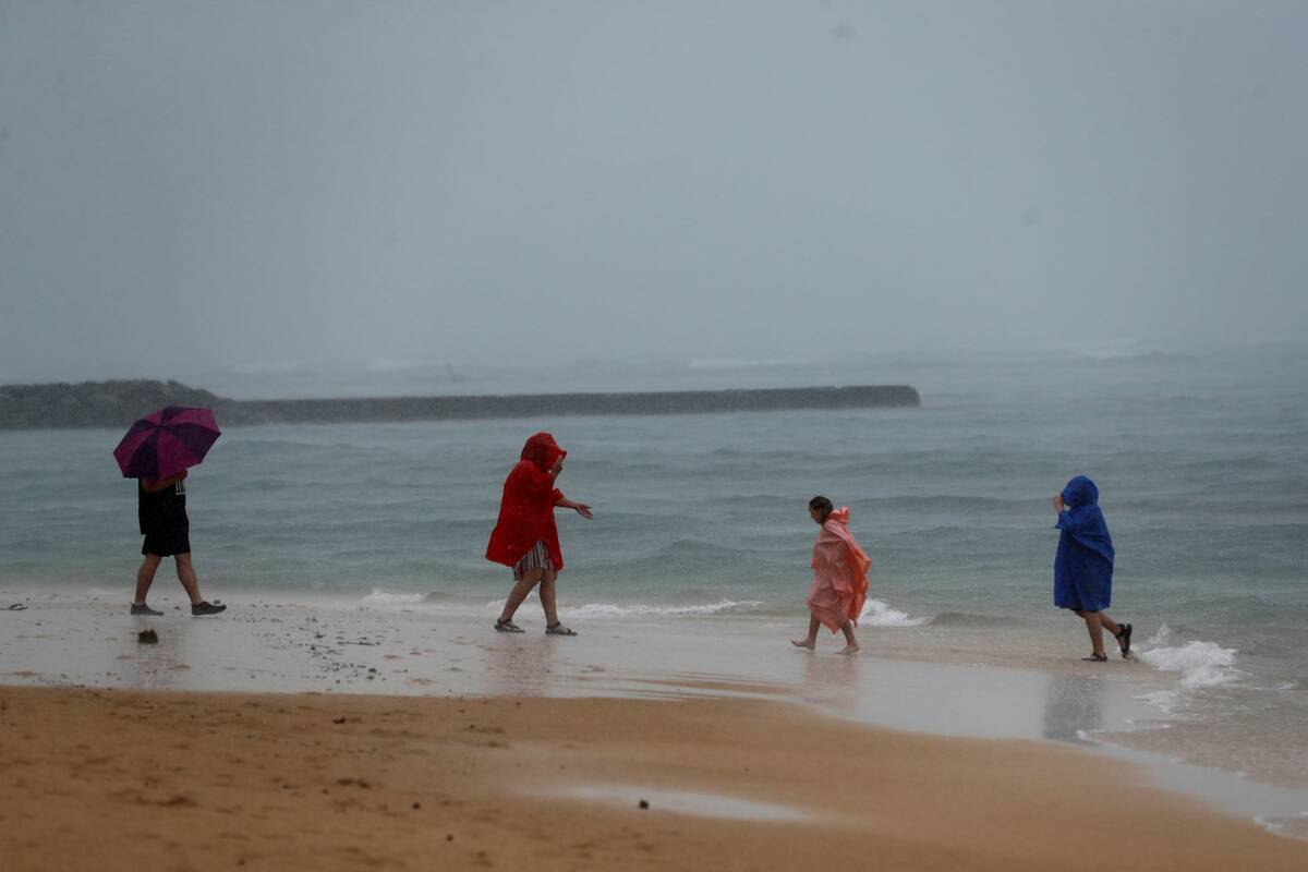 Beach goers play in the rain on Waikiki Beach, Monday, Dec. 6, 2021, in Honolulu. (AP Photo/Ma ...