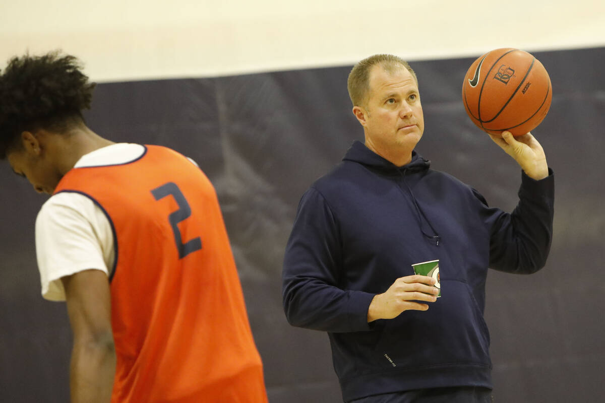 Bishop Gorman basketball head coach Grant Rice, right, holds a ball as Keenan Bey (2) walks by ...