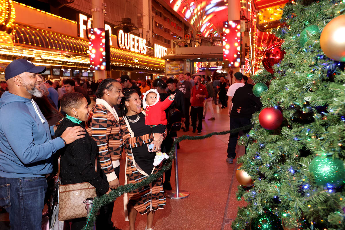 Athenasia Smith, checks out the Christmas tree with her parents Gregory and Deidre Eames, and g ...