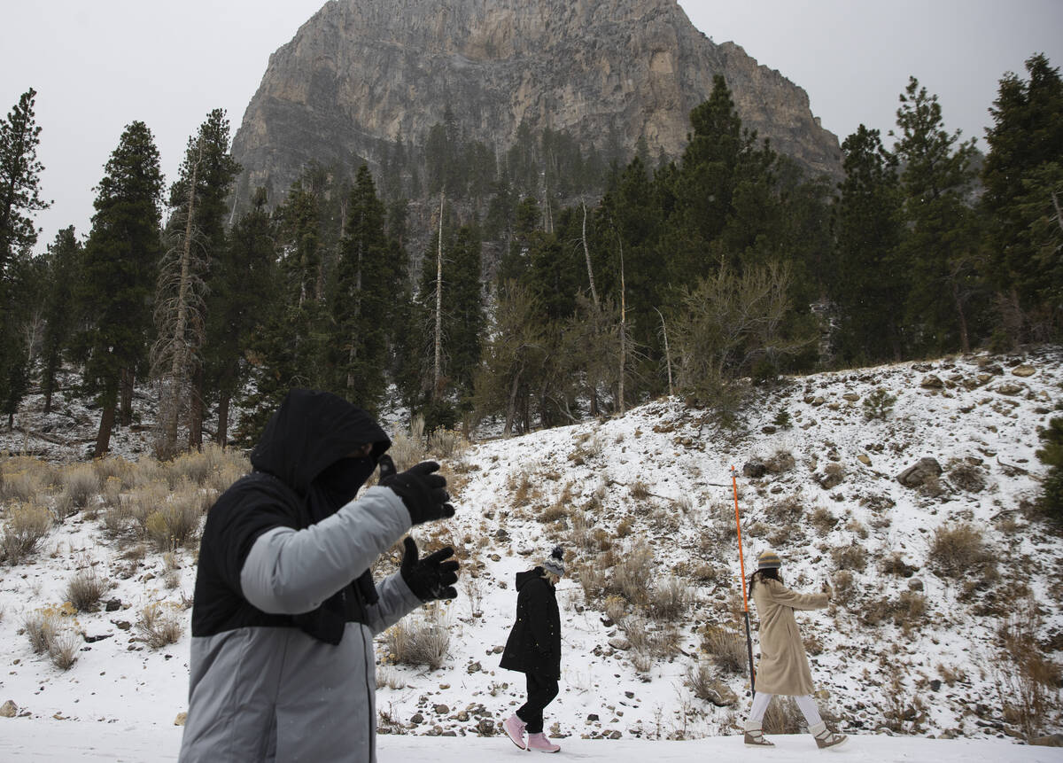 People walk along snow covered road as light snow fall on the Mt. Charleston area on Thursday, ...