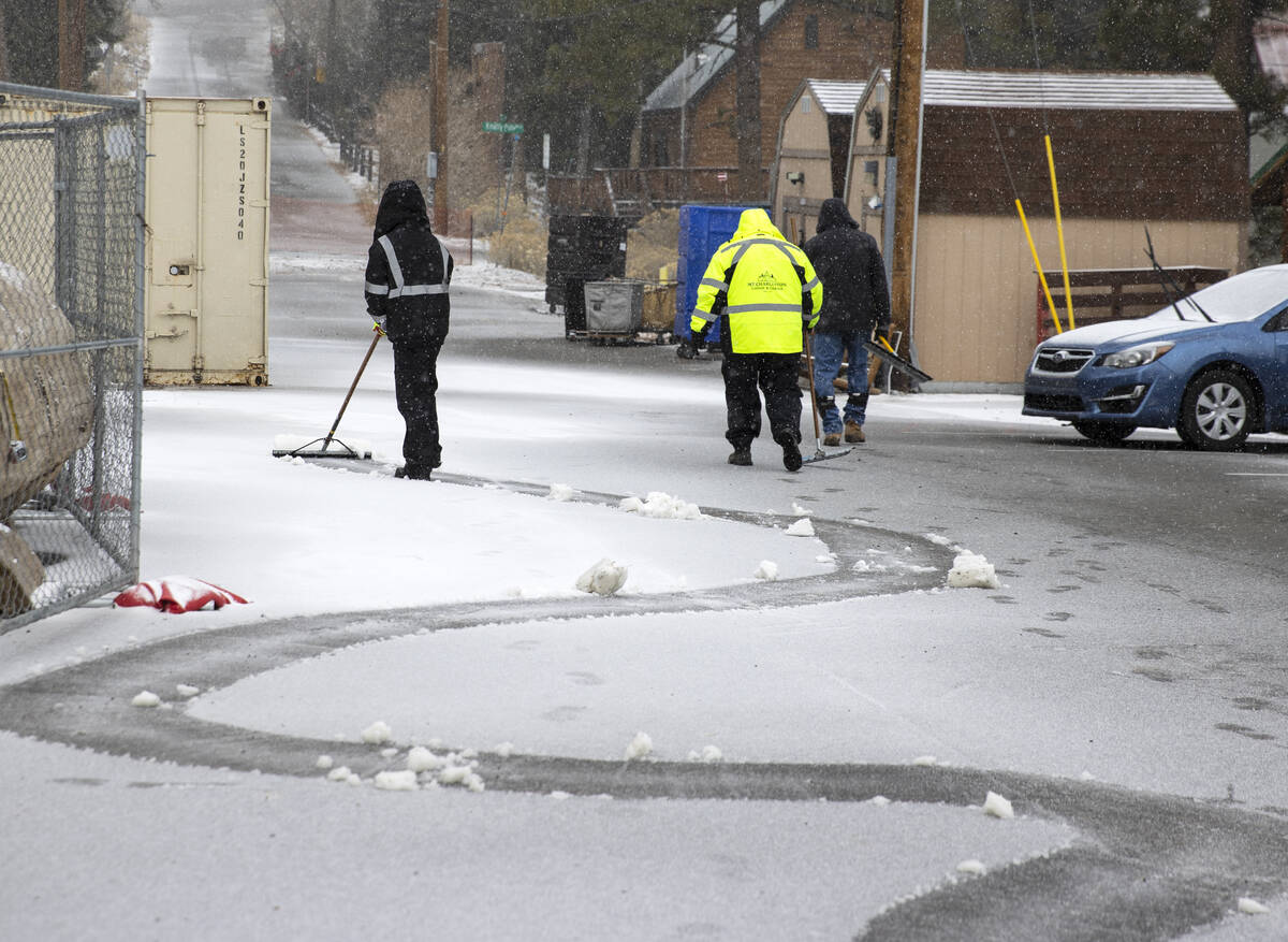 Workers at the Mt. Charleston Lodge cabins clear snow from the parking lot as light snow fall o ...