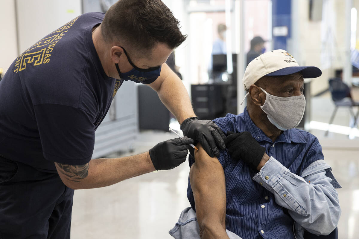 North Las Vegas Fire Department Batallion Chief Jeff Hurley administers the COVID-19 vaccine to ...