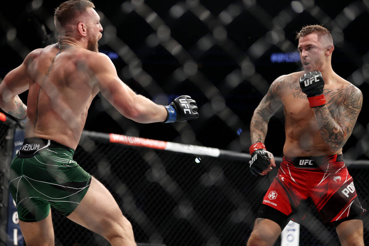Conor McGregor, left, reacts after hurting his foot in the first round of a lightweight bout ag ...