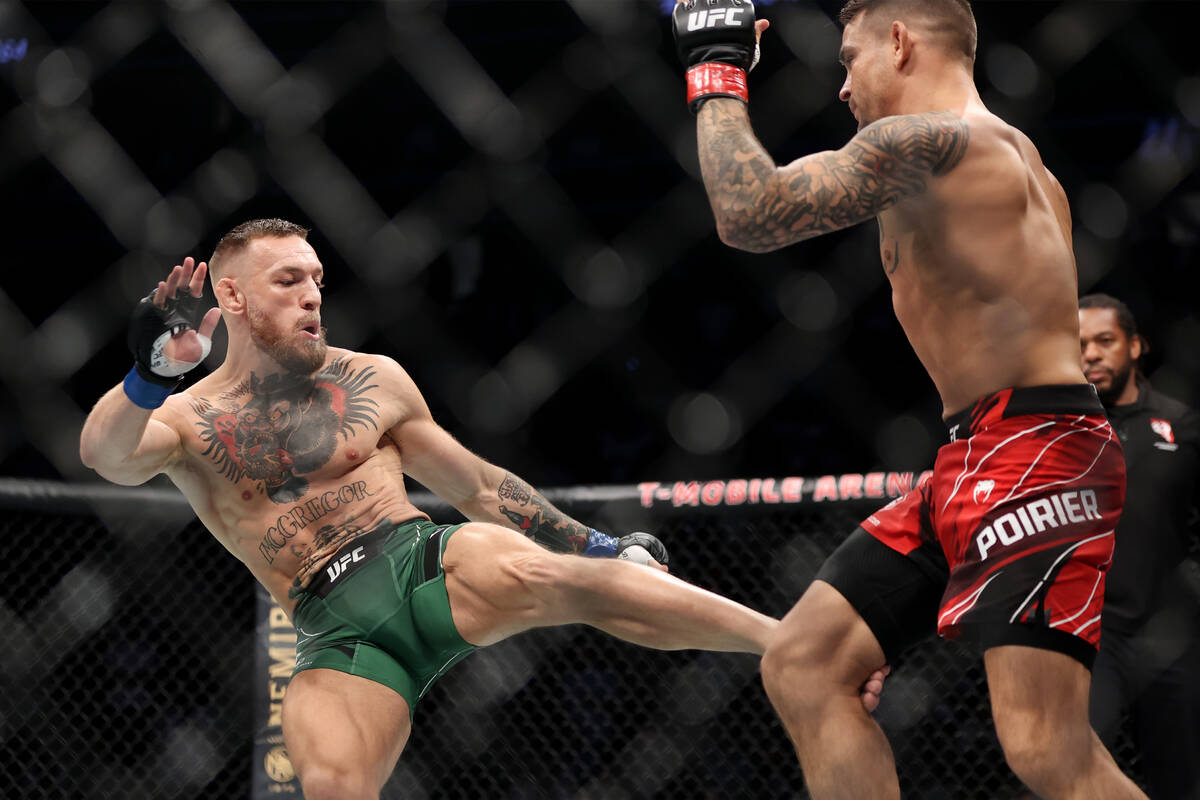 Conor McGregor, left, kicks Dustin Poirier in the first round of a lightweight bout during the ...