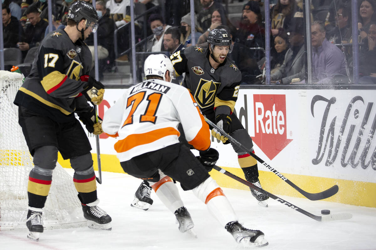 Golden Knights defenseman Shea Theodore (27) looks to pass next to defenseman Ben Hutton (17) w ...