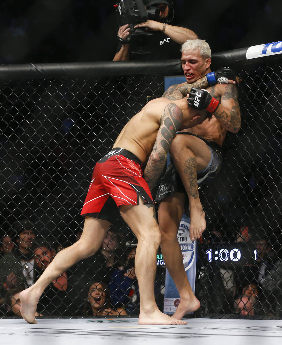 Charles Oliveira, right, delivers a knee to Dustin Poirier during a lightweight mixed martial a ...