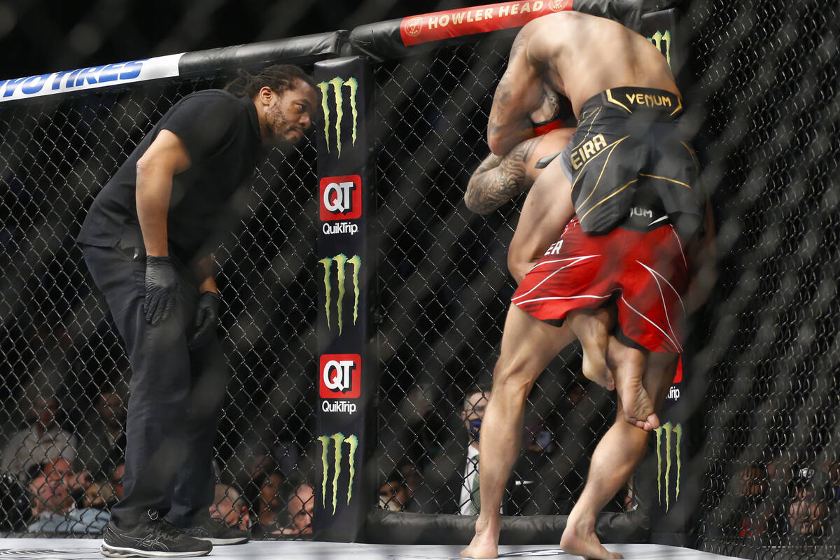 An official watches as Charles Oliveira, above, wraps up Dustin Poirier during a lightweight mi ...