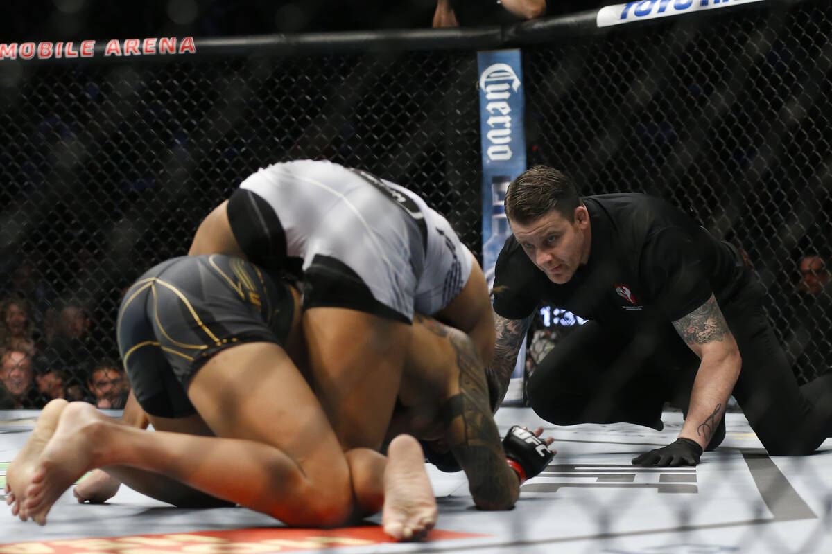 An official watches as Julianna Pena, top, moves to defeat Amanda Nunes by submission during a ...