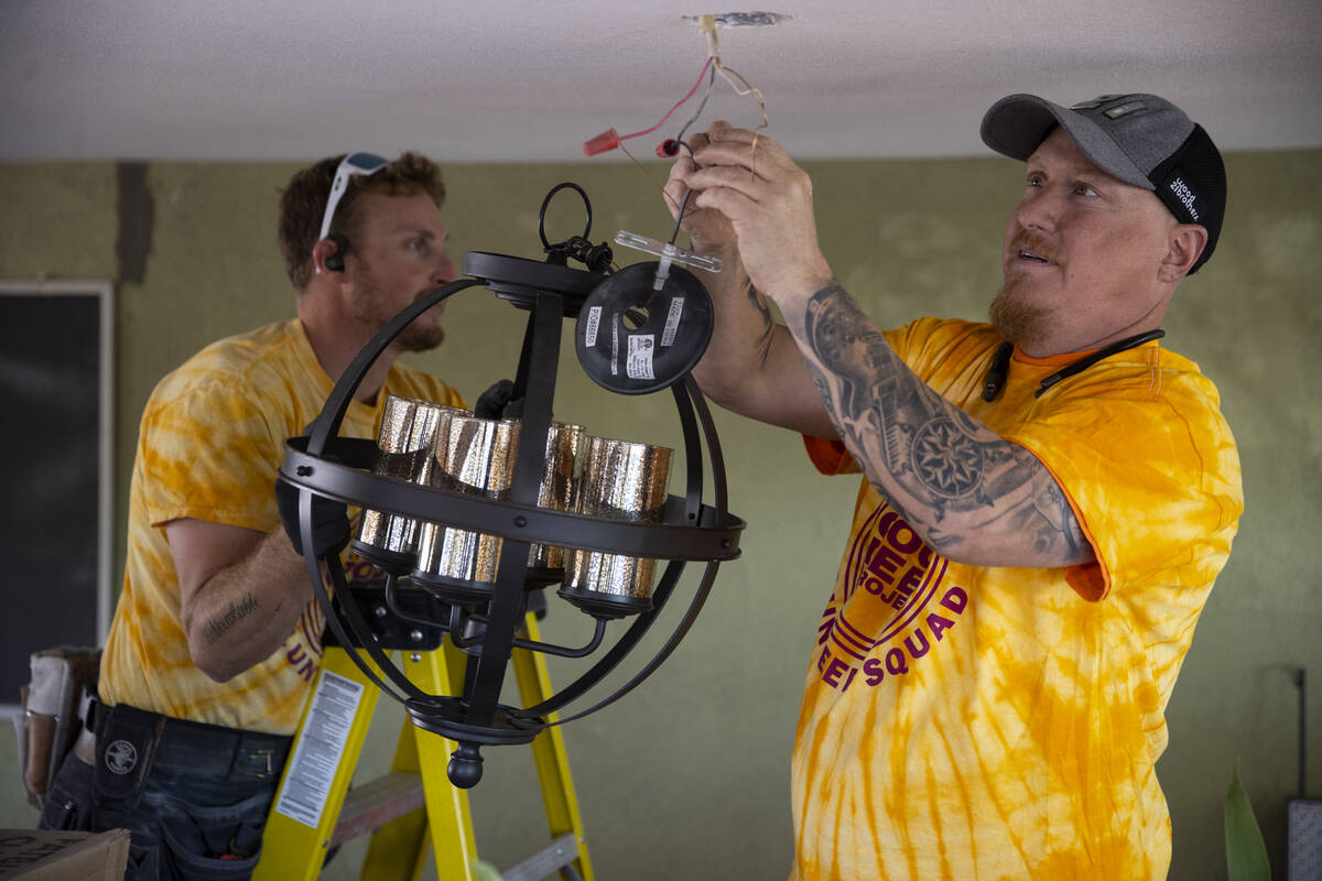 Volunteers Kyle Taylor, left, and Chad Scott, install a new light fixture as part of a home ren ...