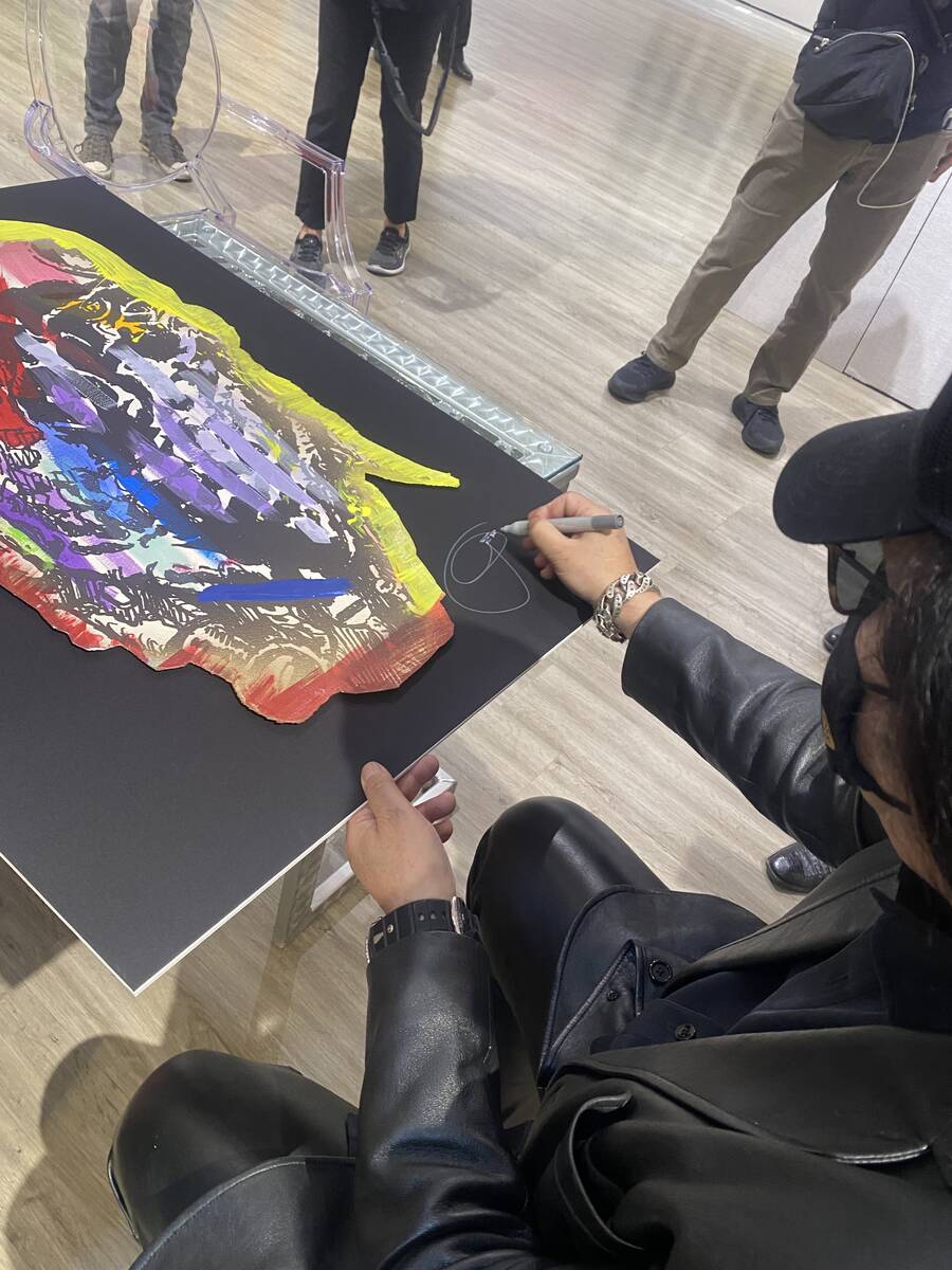Gene Simmons of Kiss is shown signing one of his original paintings at The Grand Canal Shoppes ...