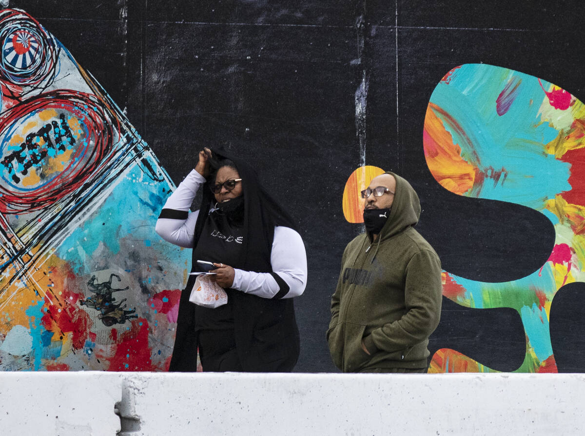 Pedestrian wearing warm clothes walk along Las Vegas Boulevard during rainy and windy Tuesday, ...