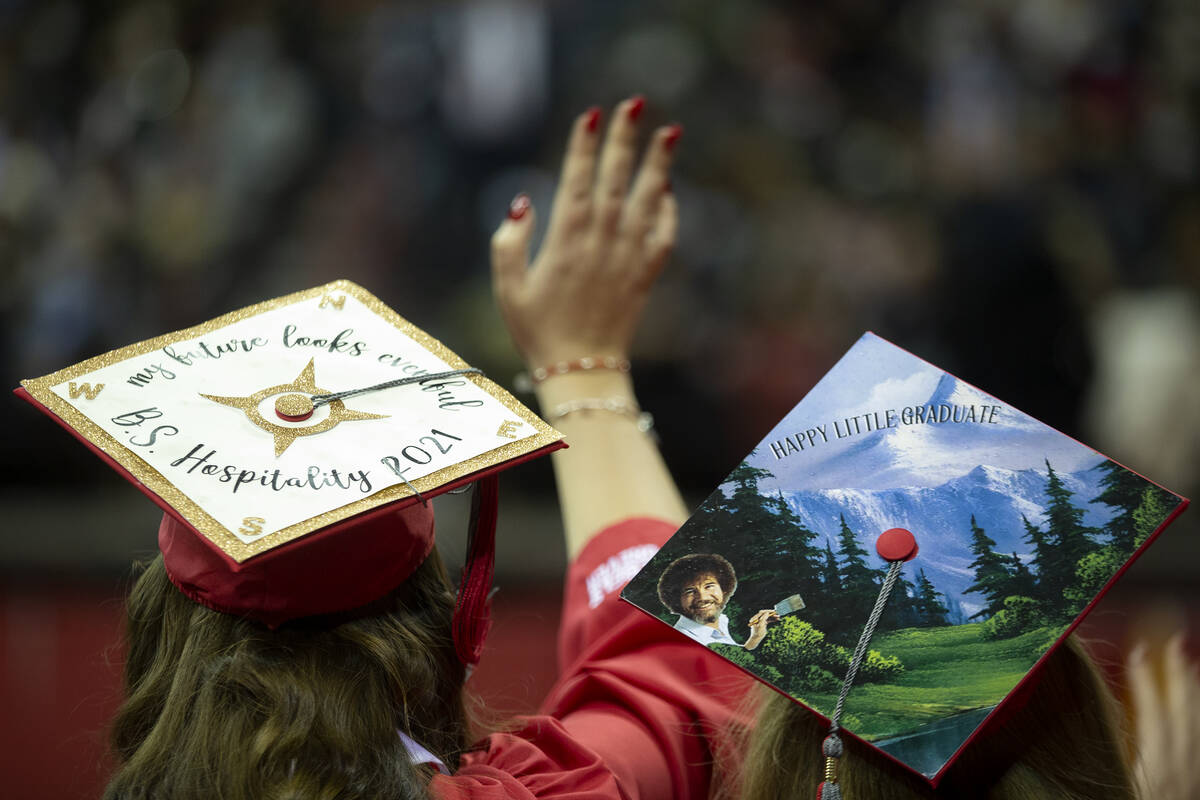 UNLV graduates with decorated caps wave to the audience during commencement at the Thomas & ...