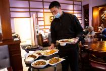 Food runner Benjamin Chancharoenroj delivers food to diners at Lotus of Siam, 620 E. Flamingo R ...