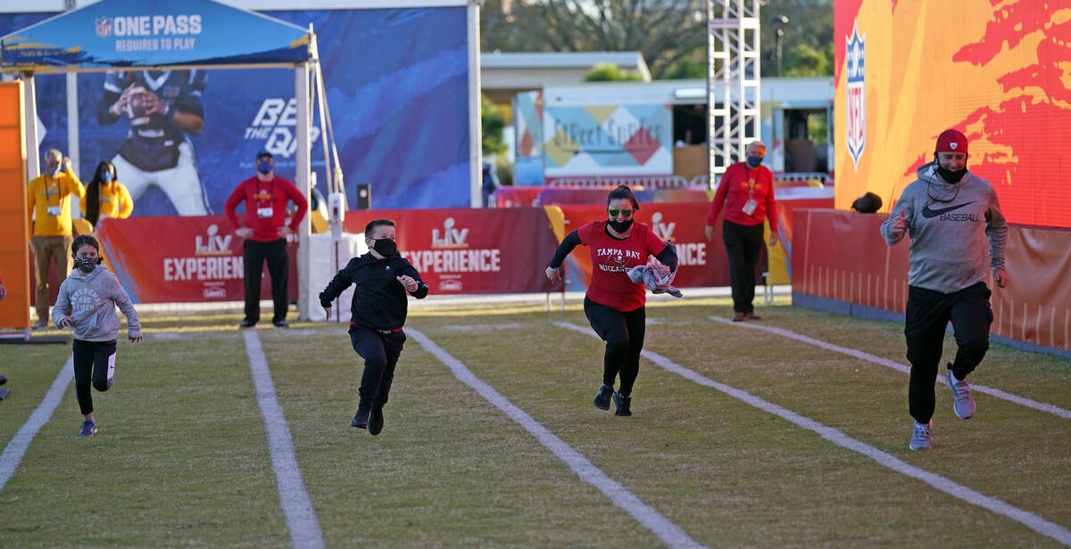 A family runs the 40-yard dash at the NFL Experience for Super Bowl LV Friday, Jan. 29, 2021, i ...