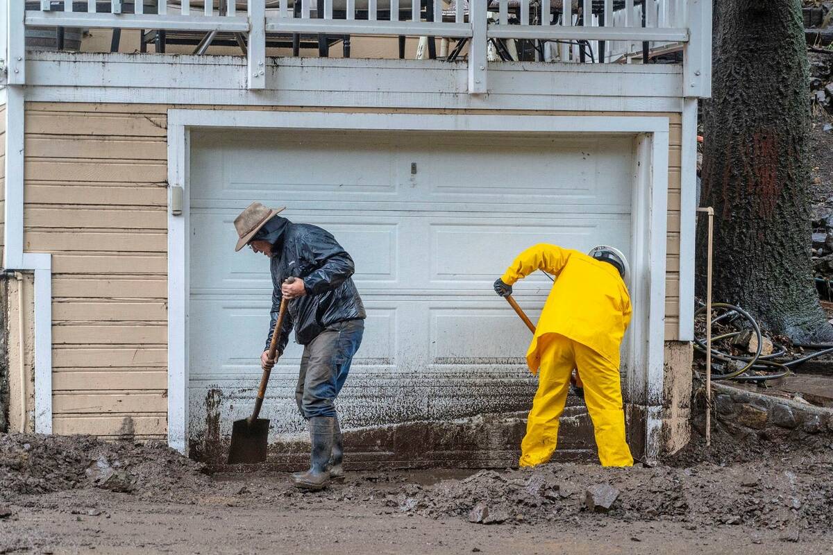 Residents dig out from a mudslide covering part of Silverado Canyon Road in Silverado, located ...