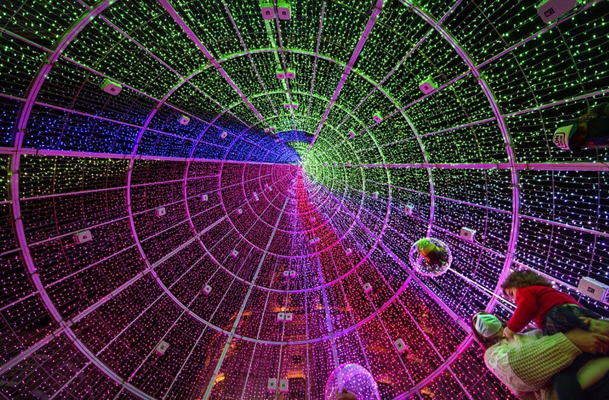 A woman holds a child as they stand inside a Christmas tree made of lights in Vigo, Spain, Sund ...