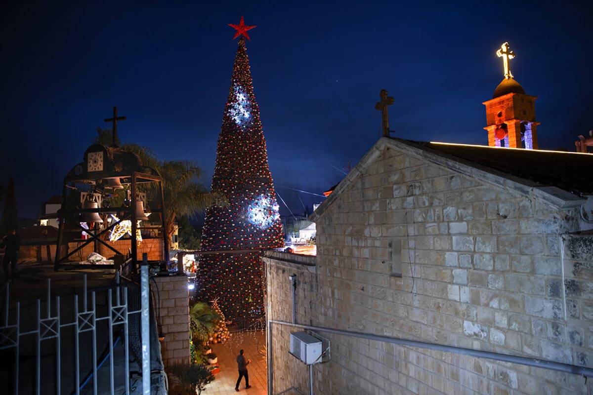 A man walks by a Christmas tree during the lighting ceremony, outside the Greek Orthodox Church ...