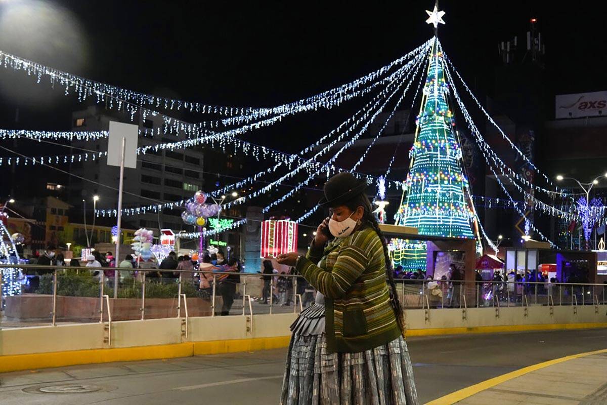 An Aymara woman talks on her cell phone at the Tejada Sorzano square adorned with holiday light ...