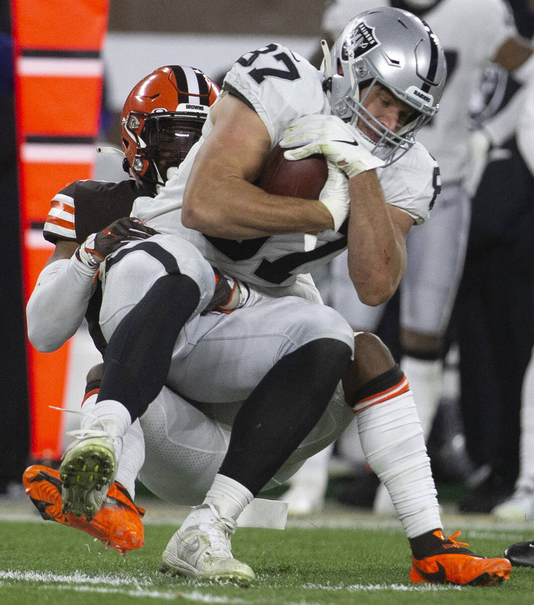 Raiders tight end Foster Moreau (87) holds on after making a catch as he is tackled by Clevelan ...