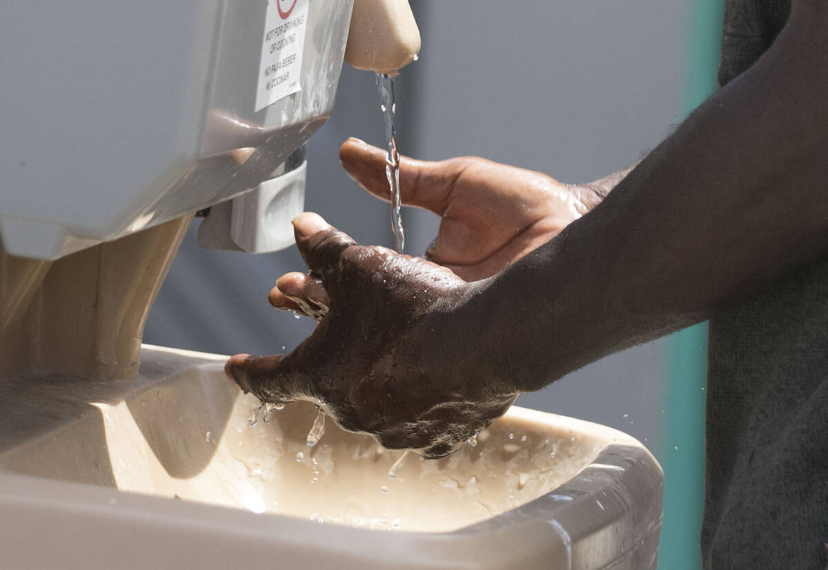 A man washes his hands at The Courtyard Homeless Resource Center in May 2020 in Las Vegas. (Biz ...