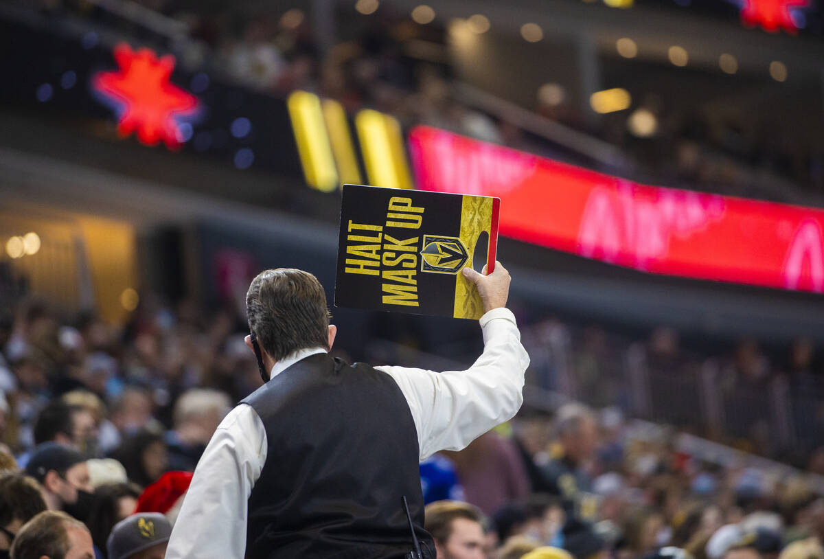 A Golden Knights usher holds a mask up sign during an NHL hockey game against the Tampa Bay Lig ...
