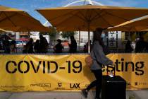 Travelers wait in line to get tested for COVID-19 at Los Angeles International Airport in Los A ...