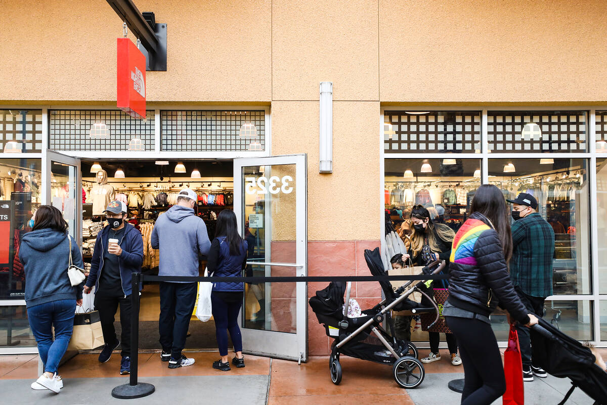 Shoppers wait outside a store at the Las Vegas South Premium Outlets on Thursday, Dec. 23, 2021 ...