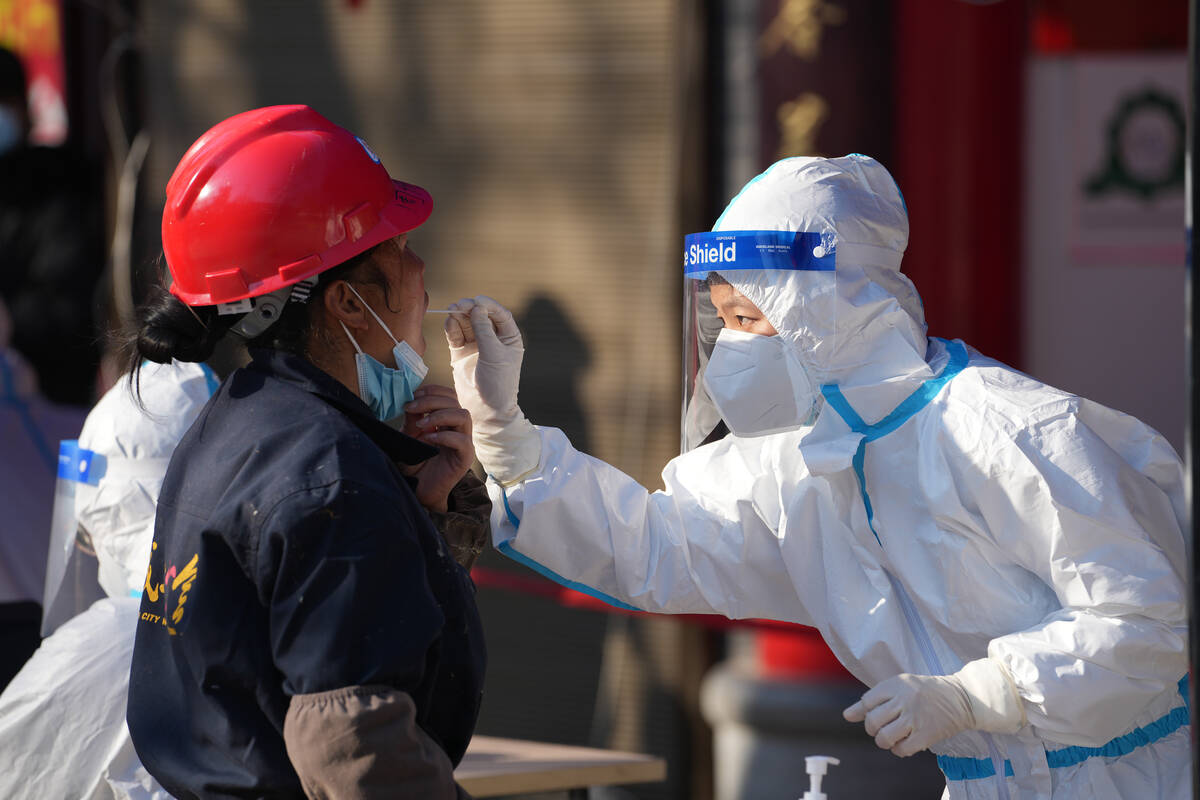 In this photo released by China's Xinhua News Agency, a worker wearing a protective suit collec ...