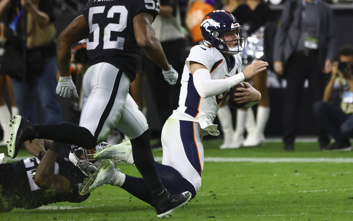 Denver Broncos quarterback Drew Lock, right, gets tripped up by Raiders defensive back Keisean ...