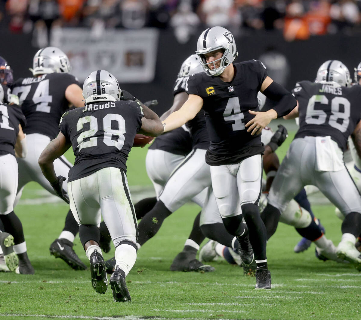 Raiders quarterback Derek Carr (4) hands off the ball to Raiders running back Josh Jacobs (28) ...