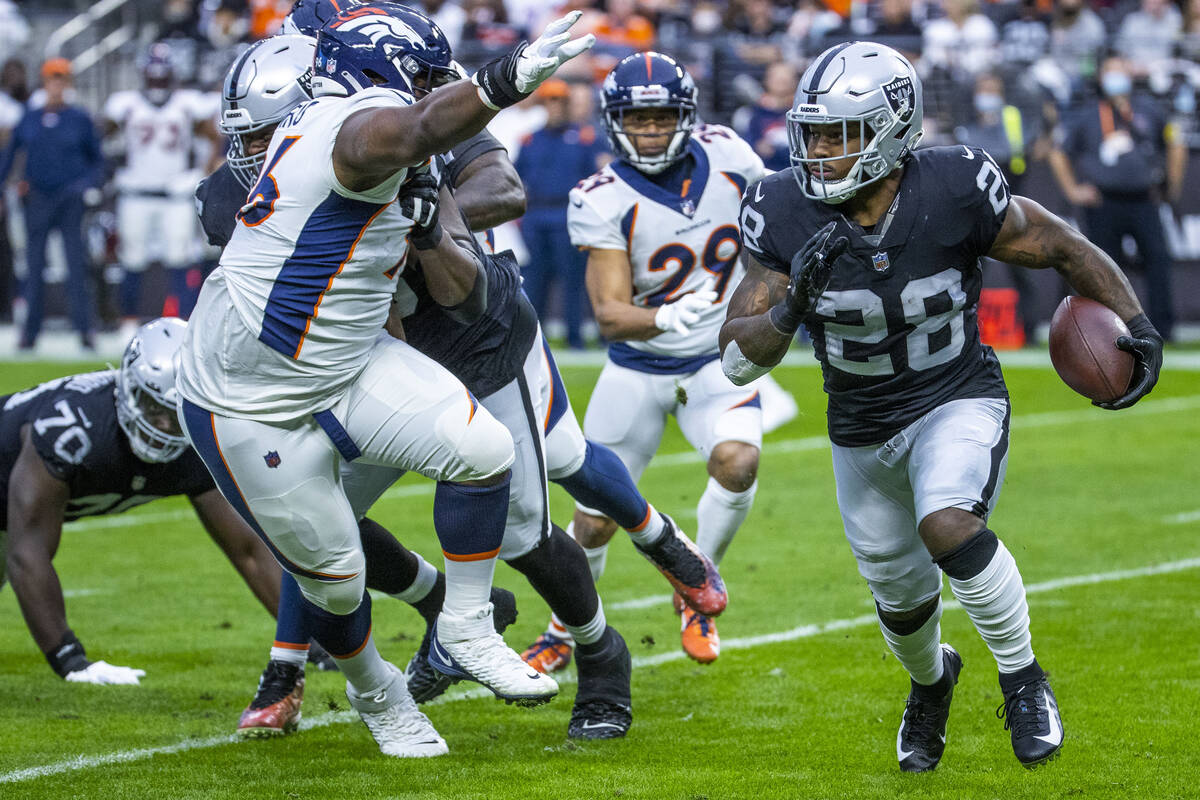 Raiders running back Josh Jacobs (28) looks to turn the corner on Denver Broncos defensive end ...