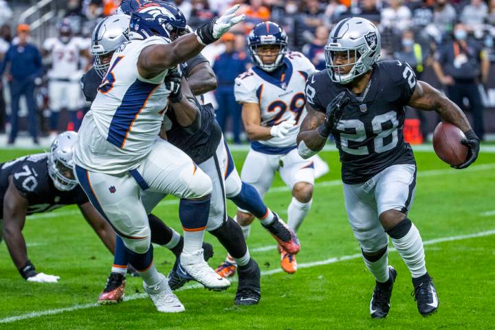 Raiders running back Josh Jacobs (28) looks to turn the corner on Denver Broncos defensive end ...