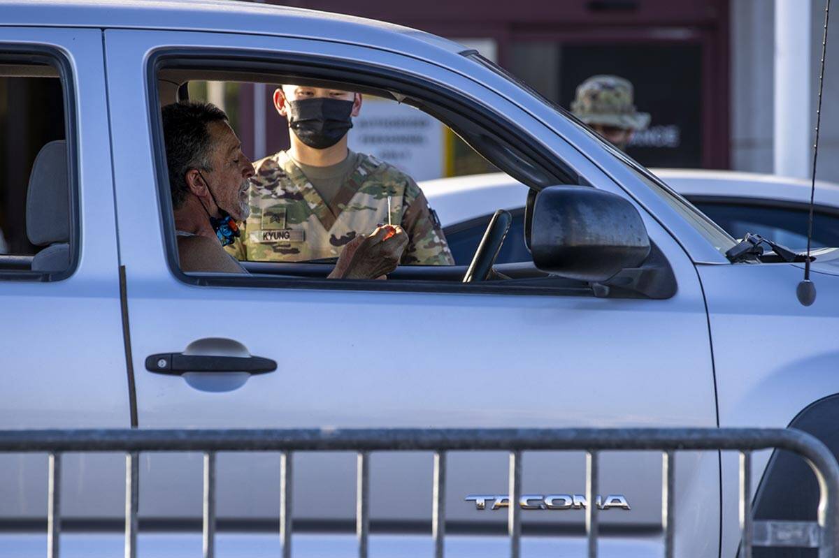 A patient uses a nose swab for a drive-thru COVID-19 test where vaccination are offered five ni ...