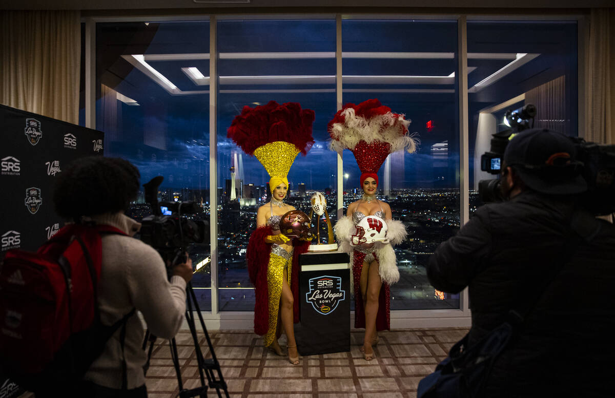 Showgirls Jennifer Autry, left, and Porsha Revesz hold helmets representing Arizona State and W ...