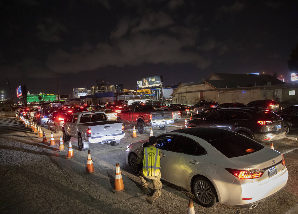 National Guard and emergency medical personnel direct traffic at a drive-thru and walk-up COVID ...