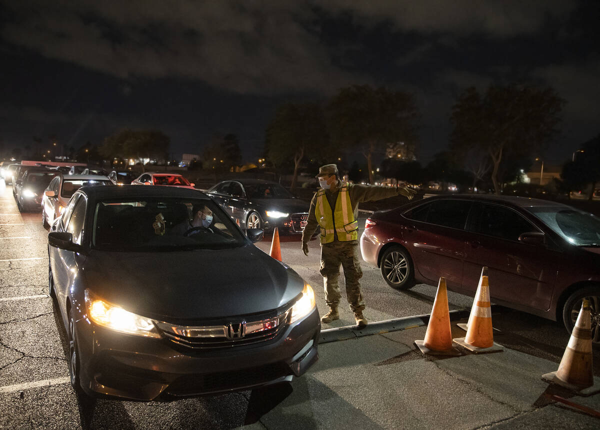 National Guard and emergency medical personnel direct traffic at a drive-thru and walk-up COVID ...