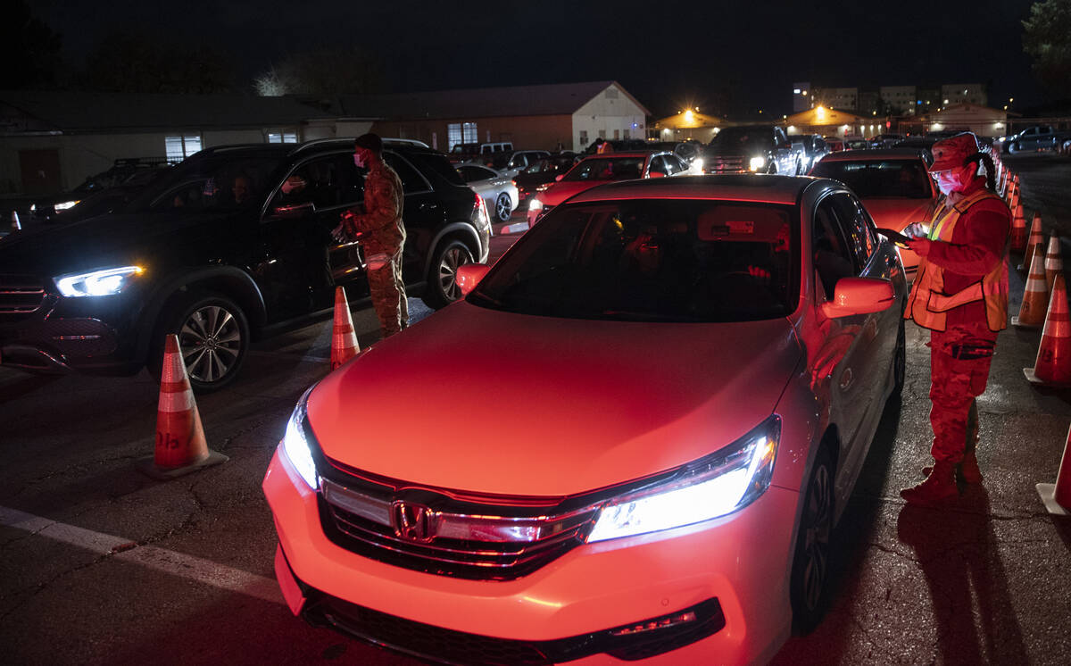 National Guard and emergency medical personnel direct traffic at a drive-thru and walk-up COVID ...